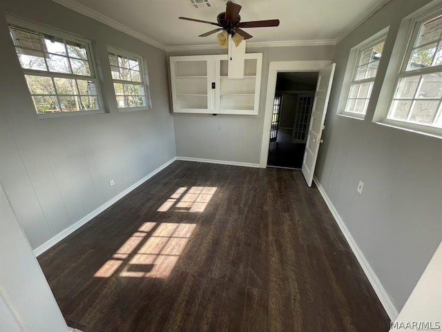 spare room with crown molding, dark hardwood / wood-style flooring, a healthy amount of sunlight, and ceiling fan