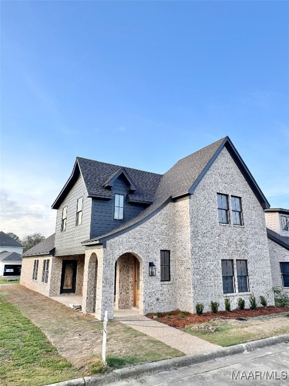 french provincial home with a front yard