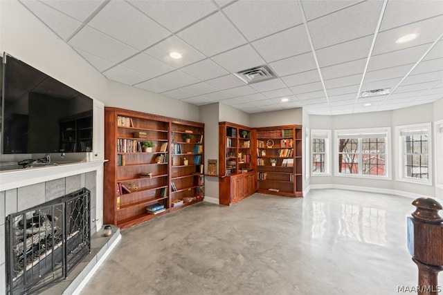 living room with a paneled ceiling and a tiled fireplace