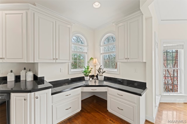 kitchen featuring dark wood-type flooring, crown molding, stainless steel dishwasher, and white cabinets