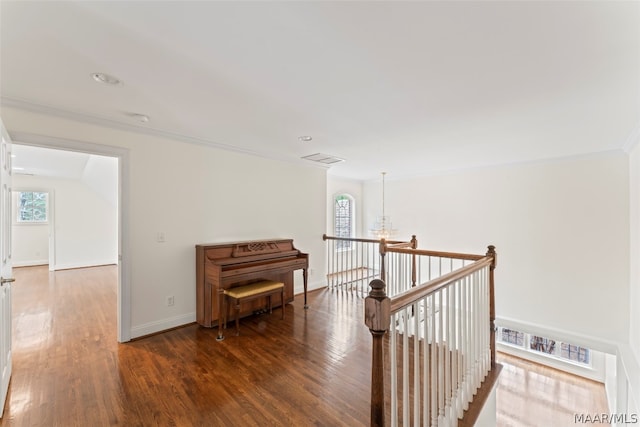 corridor with ornamental molding, dark hardwood / wood-style floors, and an inviting chandelier