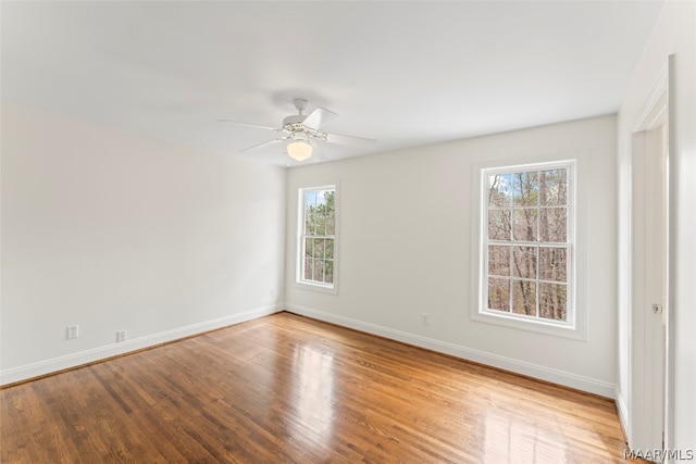 spare room with ceiling fan, light wood-type flooring, and a wealth of natural light