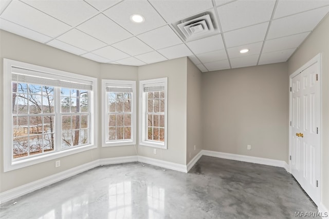 unfurnished room with a drop ceiling, plenty of natural light, and concrete flooring