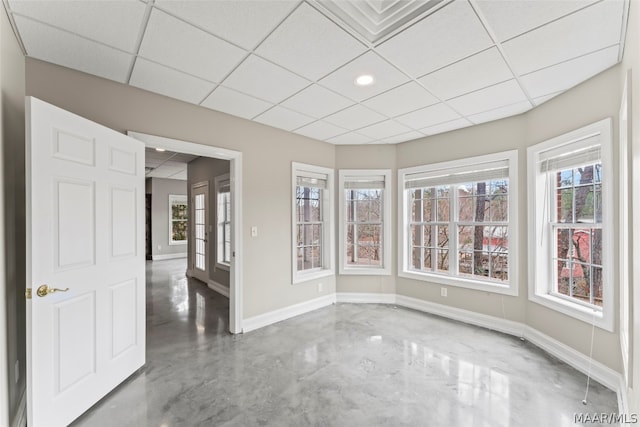 empty room featuring concrete floors and a paneled ceiling