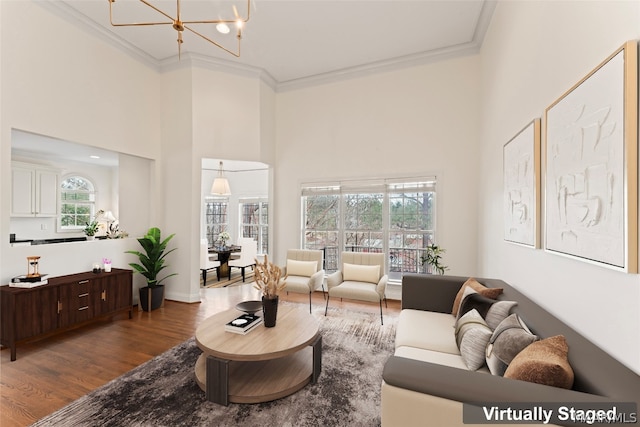 living room with a towering ceiling, crown molding, hardwood / wood-style flooring, and plenty of natural light