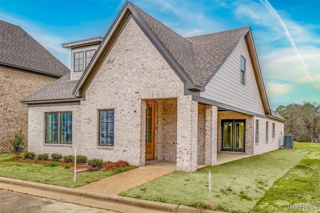 back of house featuring central AC, a patio, and a lawn