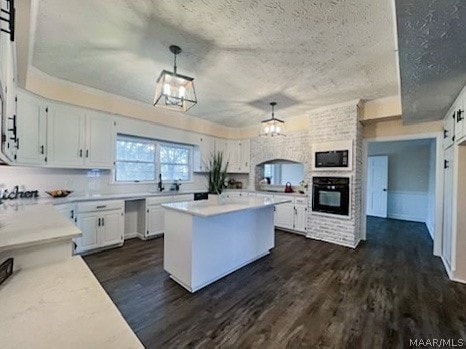 kitchen with hanging light fixtures, dark hardwood / wood-style flooring, white cabinets, black appliances, and a textured ceiling