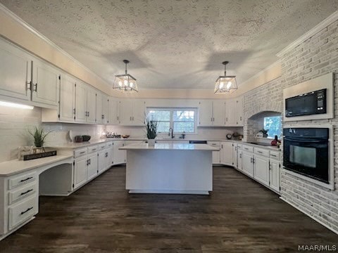 kitchen featuring white cabinets, a textured ceiling, a center island, and oven