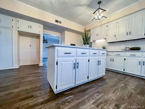 kitchen with white cabinets, a notable chandelier, dark wood-type flooring, and pendant lighting