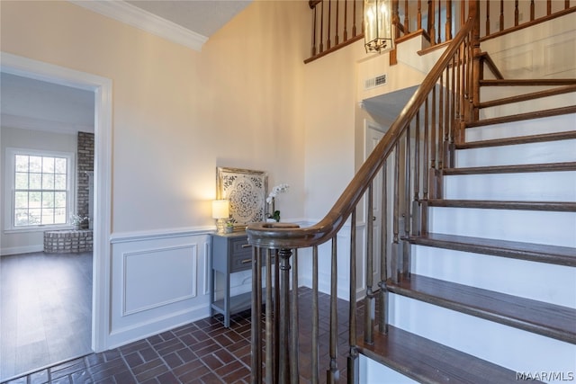 staircase featuring brick wall, ornamental molding, and dark hardwood / wood-style flooring