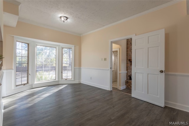 spare room with brick wall, dark wood-type flooring, a textured ceiling, and crown molding