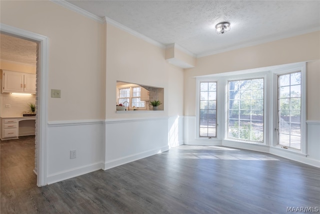 empty room featuring a textured ceiling, dark hardwood / wood-style floors, and crown molding