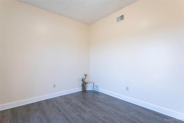 empty room with a textured ceiling and dark wood-type flooring