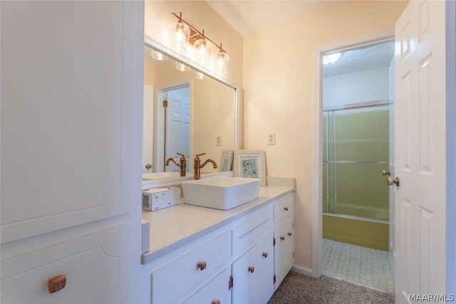 bathroom featuring a textured ceiling, combined bath / shower with glass door, and vanity