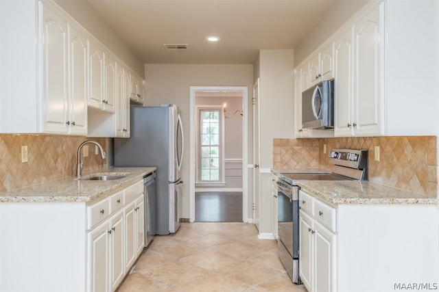 kitchen featuring appliances with stainless steel finishes, backsplash, light tile floors, sink, and white cabinets