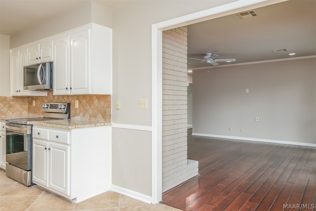 kitchen featuring ceiling fan, light stone counters, appliances with stainless steel finishes, tasteful backsplash, and white cabinetry