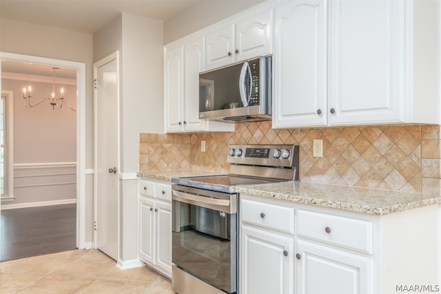 kitchen with white cabinetry, a notable chandelier, stainless steel appliances, light tile floors, and tasteful backsplash