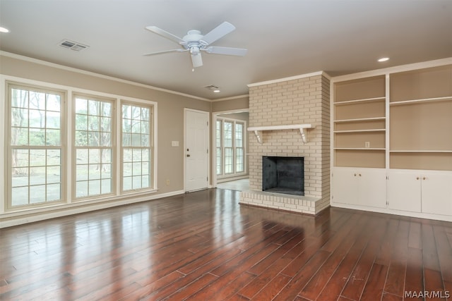 unfurnished living room with ceiling fan, ornamental molding, dark wood-type flooring, and a brick fireplace