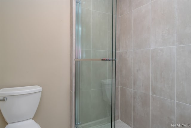 bathroom with a shower with shower door and toilet