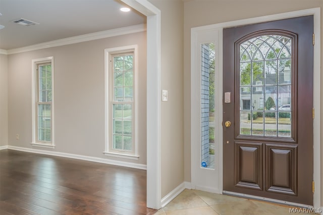 foyer with ornamental molding, a wealth of natural light, and light wood-type flooring