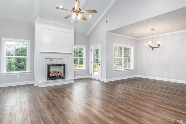 unfurnished living room featuring ceiling fan with notable chandelier, a premium fireplace, a wealth of natural light, and dark wood-type flooring