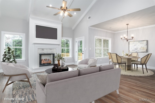 living room with ceiling fan with notable chandelier, lofted ceiling, a fireplace, and hardwood / wood-style flooring