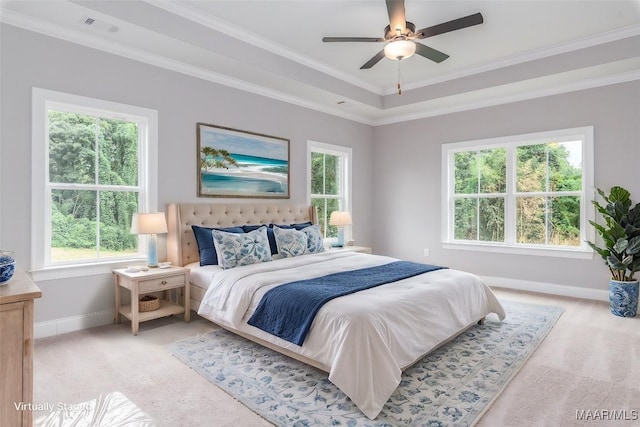 bedroom featuring ceiling fan, light carpet, crown molding, and a tray ceiling