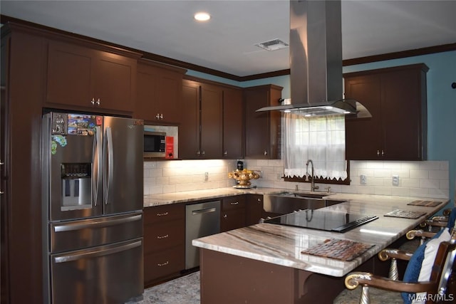 kitchen featuring decorative backsplash, kitchen peninsula, a breakfast bar area, island range hood, and appliances with stainless steel finishes