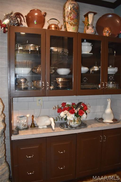 bar with dark brown cabinetry and backsplash