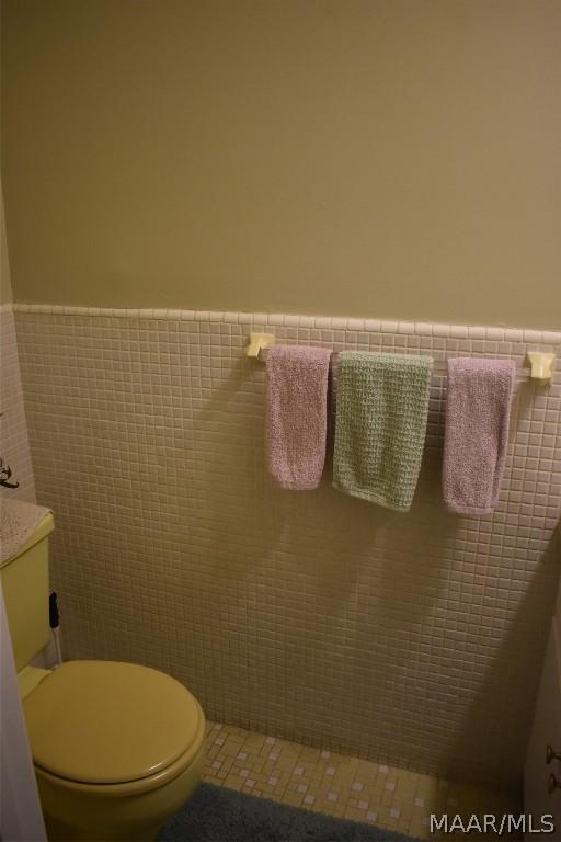 bathroom featuring tile patterned floors, toilet, and tile walls