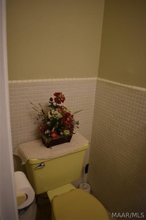 bathroom featuring toilet and tile walls