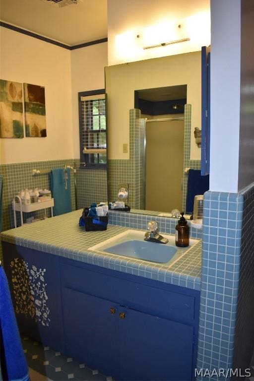 bathroom with vanity, a shower with door, and tile walls