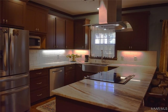 kitchen with island exhaust hood, appliances with stainless steel finishes, backsplash, light stone countertops, and ornamental molding