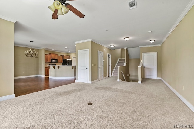 unfurnished living room with ceiling fan with notable chandelier, ornamental molding, and carpet floors