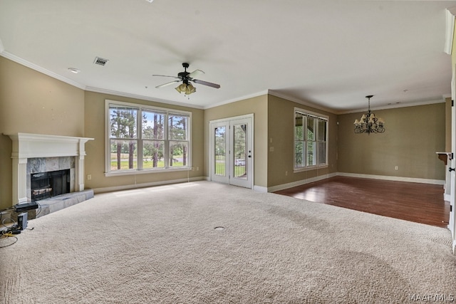 unfurnished living room with ceiling fan with notable chandelier, ornamental molding, a tiled fireplace, and dark hardwood / wood-style flooring