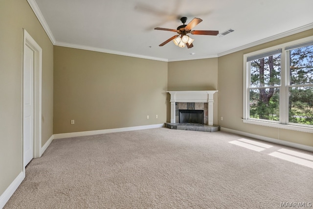 unfurnished living room with carpet flooring, a tiled fireplace, ceiling fan, and ornamental molding