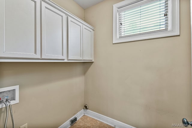 clothes washing area with tile floors, washer hookup, and cabinets