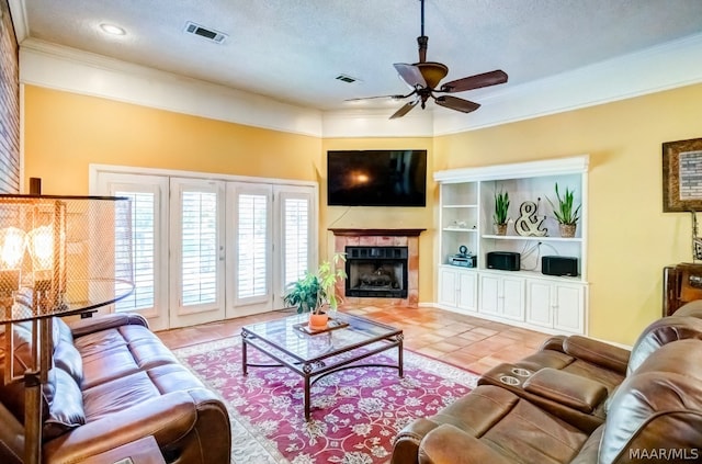 tiled living room with a textured ceiling, ornamental molding, a fireplace, and ceiling fan