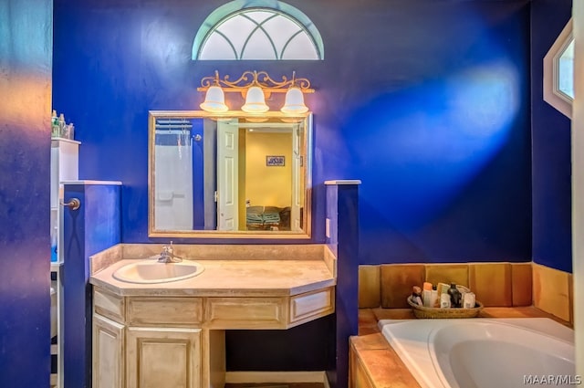 bathroom featuring tiled tub and vanity