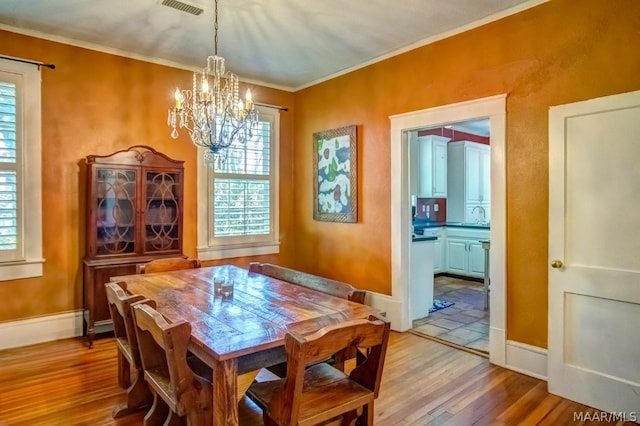 dining space with crown molding, light hardwood / wood-style flooring, and a chandelier