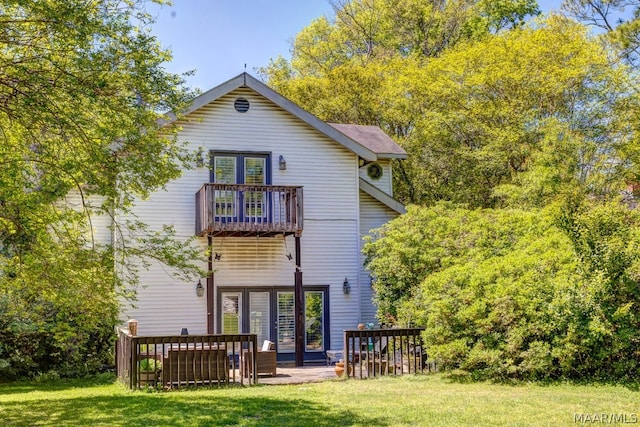 rear view of house featuring a balcony and a lawn