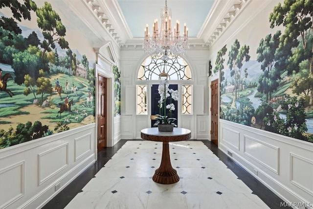 entryway featuring an inviting chandelier, a decorative wall, crown molding, and a wainscoted wall