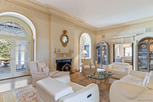 living area with ornamental molding, a wealth of natural light, french doors, and a fireplace