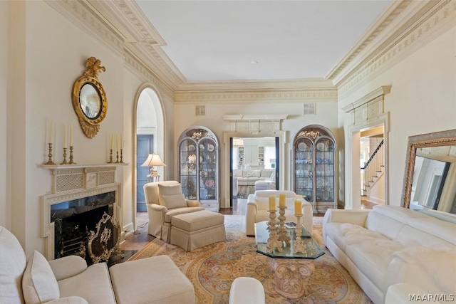 living area featuring ornamental molding, a premium fireplace, wood finished floors, and visible vents