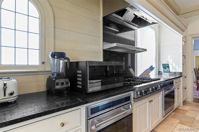 kitchen with stainless steel appliances, stone finish floor, crown molding, and decorative backsplash