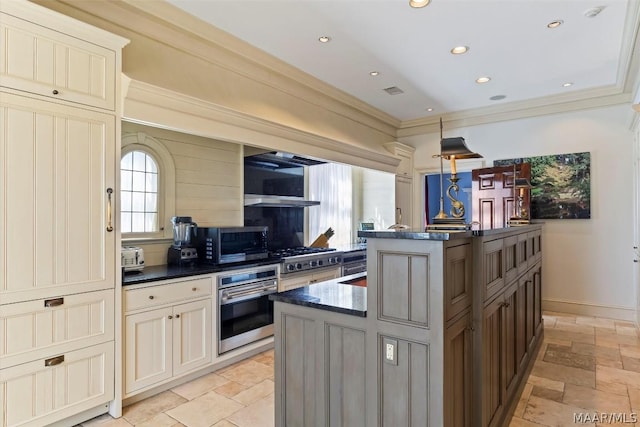 kitchen featuring appliances with stainless steel finishes, dark countertops, a center island with sink, and stone tile flooring