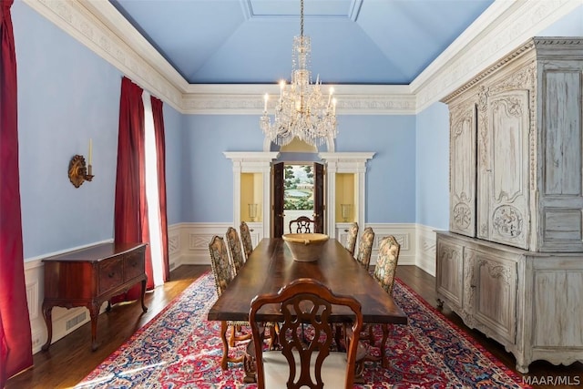 dining area with a chandelier, vaulted ceiling, and wainscoting