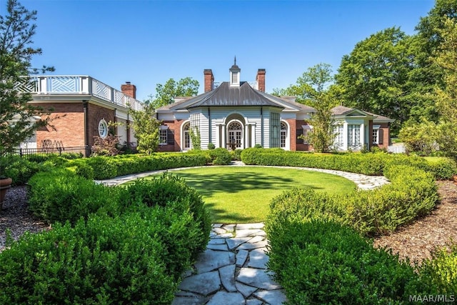 view of front facade featuring a front yard, brick siding, and a chimney