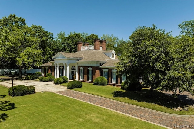 greek revival inspired property with a chimney and a front lawn