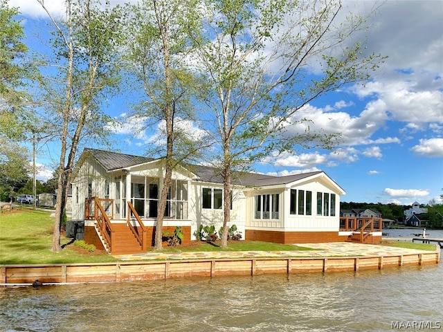 back of property featuring central air condition unit, a deck with water view, and a sunroom